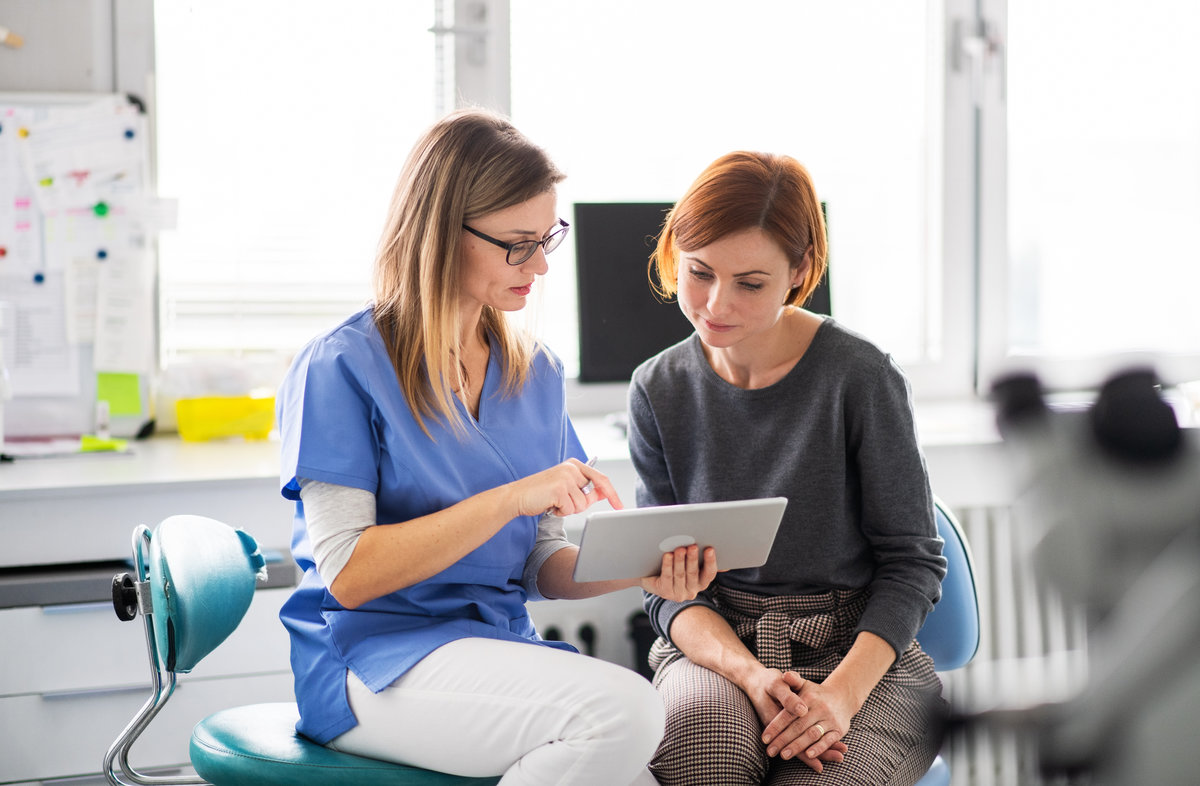 A dentist talking to woman in dentist surgery, a dental check-up.